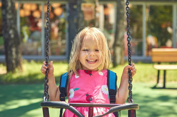 Petite fille se balançant sur une balançoire et s'amusant dans l'aire de jeux du parc — Photo