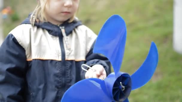 Primo piano dei bambini giocare filatura mulino a vento Elica blu all'aperto con mano — Video Stock