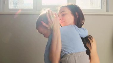 Sevgi dolu anne çocuğu kollarında tutar okşar ve ağlayan bebeğine sarılır, diş ağrısını dindirir. Sıcak aile bakımı, empati ve şefkat dolu bir ortam. Yüksek kalite 4k görüntü