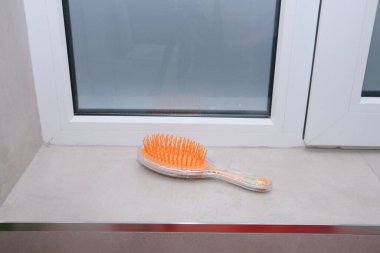 Saç fırçası banyodaki çıkıntıda oturup kullanılmayı bekliyor. Görüntü kişisel hijyen, kişisel bakım ve günlük rutinleri temsil ediyor. Güzellik, sağlık ve yaşam tarzı içeriği için ideal