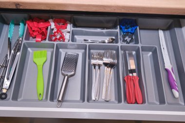 İyi organize edilmiş mutfak gereçleri çekmecesinde maşalar, spatulalar, ızgaralar, çatallar, bıçaklar ve çeşitli yemek aletleri var. Pratik depo. Yerli. Çok güzel. Düzenli. Yemek pişirme