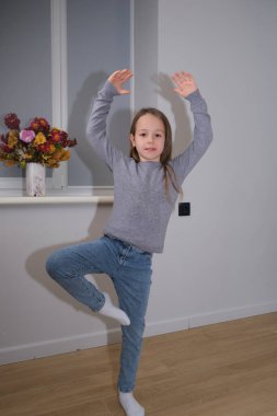 Neşeli bir kız, çiçeklerle dolu parlak bir odada bale yapıyor. Bu çekim bir çocuğu oyunda yakalar, dans, çocukluk veya aile hayatı ile ilgili konular için harikadır.