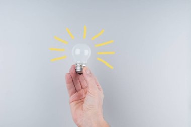 Gri arkaplanda el ele tutuşan ampul