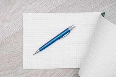 Tahta arka planda not defteri ve kalem. Üst görünüm