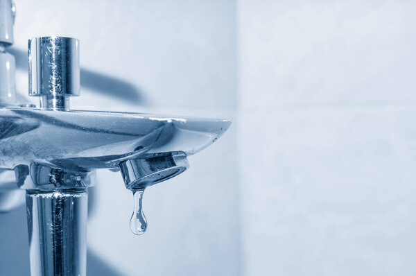 Кран и капля чистой воды вблизи