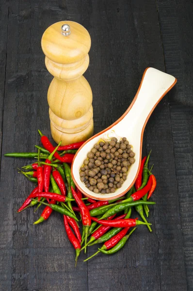 Hot pepper and mill on wooden background — Stock Photo, Image