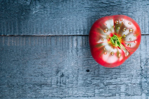 Tomato with drops on wooden background — Stock Photo, Image