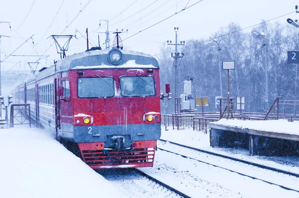 Поезд прибывает на железнодорожную платформу в снежную метель — стоковое фото