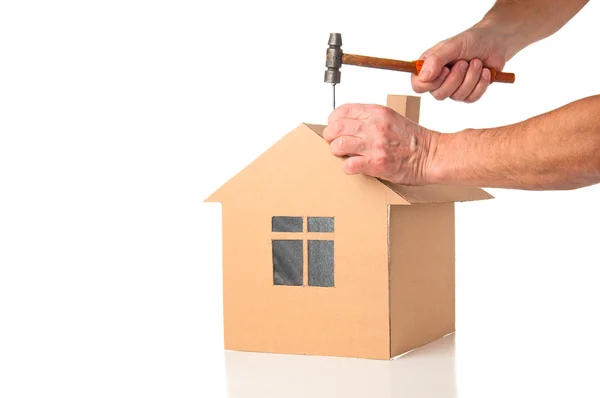 Człowiek opiera się model kartonowy domu — Zdjęcie stockowe