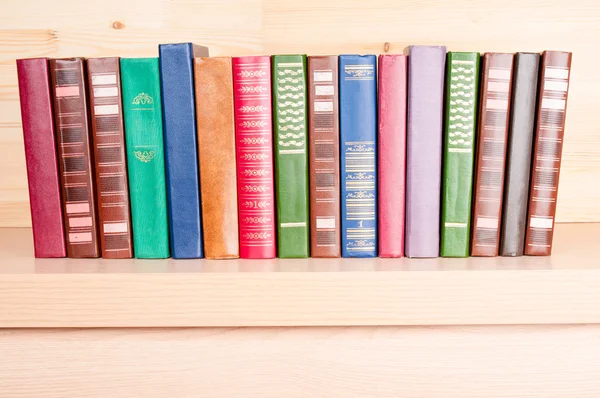 Oude kleurrijke boeken op houten plank — Stockfoto