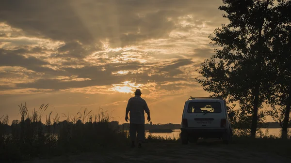 Shadow man of travel trip on summer evening man stand near a car and lake — Stock Photo, Image