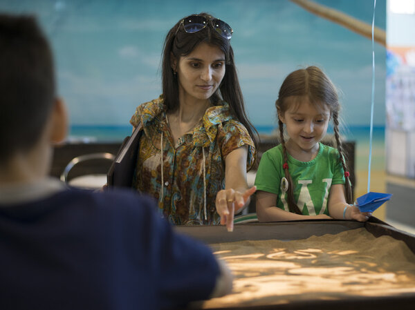 Mom and daughter painted on the sand. Table drawing sand.