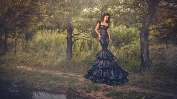 Girl in a very long dress. Walk down the path along the pond. — Stock Photo, Image