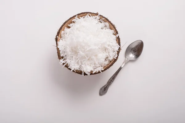 Rasage de noix de coco dans un bol de pot, une partie d'une noix de coco et une cuillère sur un fond blanc — Photo