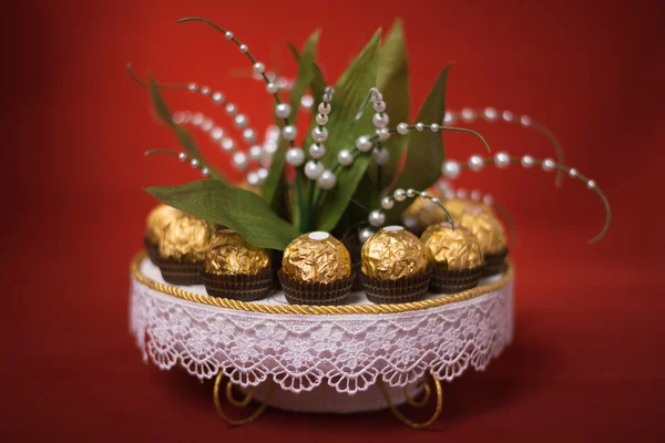 Bouquet from candies a lily of the valley beautiful with shekoladny candies in a gold wrapper on a red background