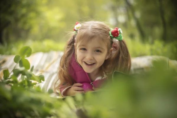 Niña 4,5,6 años con horquillas de una fresa yace sobre una hierba en el parque —  Fotos de Stock
