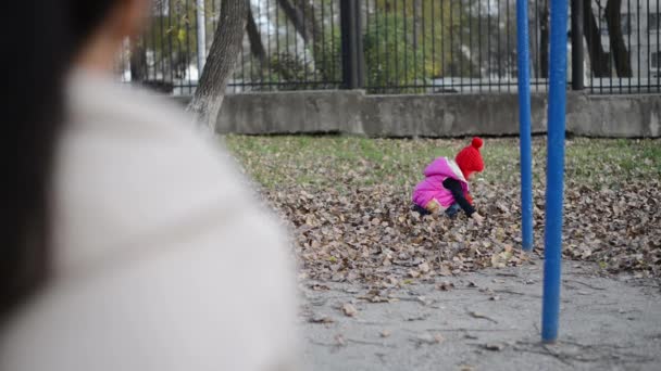 Fille jouer avec les feuilles sèches tombées ... — Video