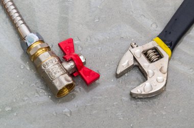 Bir kaza sırasında ekipman onarımı sırasında musluk ve ingiliz anahtarı su damlalarına konmuş.