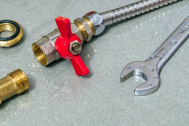 Tesisat musluğu ve ingiliz anahtarı bir kaza sırasında ekipman onarımı sırasında damlalar.