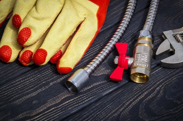 Hoses and work gloves on vintage boards. The working environment of master plumber