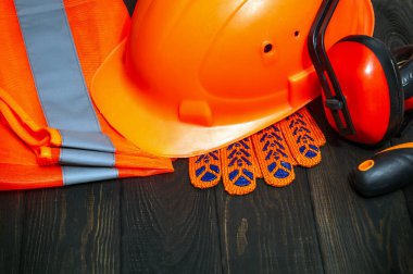 Ana müteahhitin turuncu koruyucu ekipmanı ve işe gitmeden önce kara tahtalara istiflenmiş araç