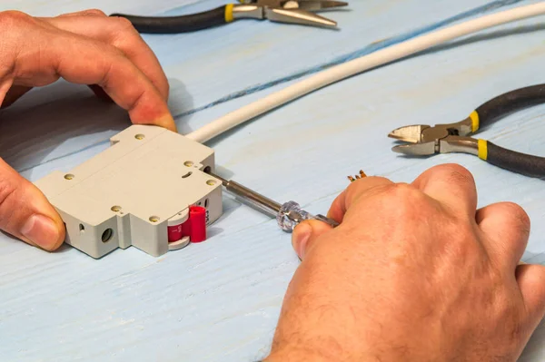 Master electrician connects electrical cable and circuit breaker with a screwdriver