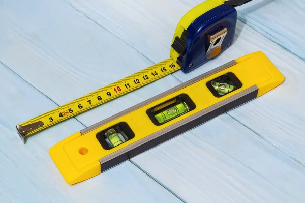 Building level and tape measure for leveling or measuring objects on blue boards
