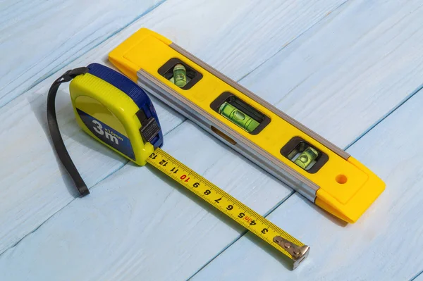 Building level and construction tape measure for leveling or measuring objects on blue boards