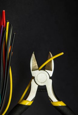 Çapraz kesiciler ve sarı kablolar siyah arkaplanı kapatıyor. Elektronik Onarım Fikri