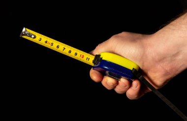 Siyah izole edilmiş arka planda inşaat bandı tutan bir adam.