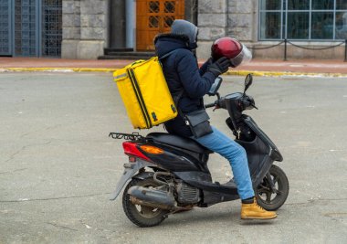 Scooter 'da yemek kutusuyla paket servis yapan çocuk. Kafelerden ve restoranlardan ekspres yemek servisi. Moto scooter 'daki kurye yiyecek getiriyor.