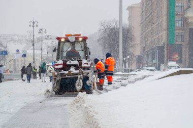 Kar temizleme aracı karı kaldırıyor. Yoğun kar yağışından sonra traktör ve işçiler yolu açıyor