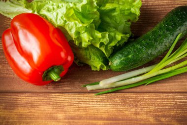 Antika bir masada taze otlar, salatalıklar ve kırmızı biberden salata yapmaya hazır.