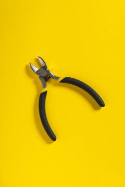 Sarı arka plandaki çapraz pense elektrik kablolarını kesmek için kullanılır. Usta bir elektrikçi için gerekli araç