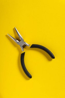 Sarı arka plandaki çapraz pense genellikle elektriği onarmak için kullanılır. Usta bir elektrikçi için gerekli bir araç