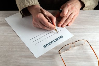 Masaüstünde çalışan bir ortamda ipotek çiziyorum. Erkek ellerinin kalemle doldurduğu yakın plan.