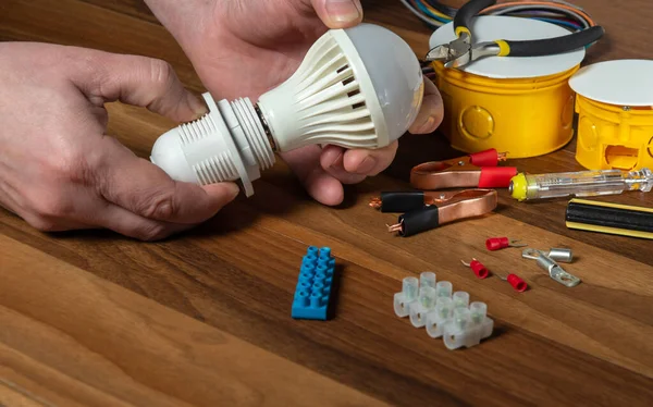 Master electrician turns on the light bulb. Close up of a worker hand on the desktop