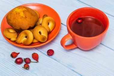 Turuncu tabakta kek ve gül çayı ile ev yapımı yuvarlak simit. Lezzetli bir kahvaltı ya da akşam yemeği fikri.