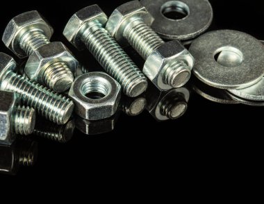 Siyah izole bir arkaplanda birçok metal cıvata ve fındık parçaları birleştirmek için kullanılır.