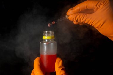 Kimyager elinde asit ile test tüpü tutuyor. Kimyasalların karıştırılmasından kaynaklanan bir reaksiyon sonucu buhar ya da duman