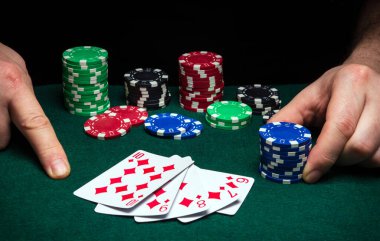 Kumarbazın elleri yakın planda ve poker kulübünde yeşil masada. Bir oyuncu kazanma pokerine para yatırır.