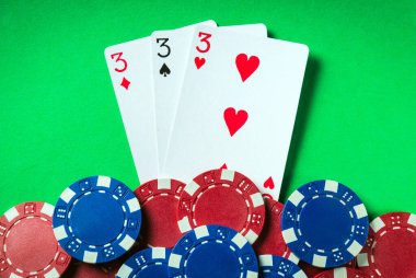 Kazanan poker kombinasyonu üç çeşit ya da set. Poker kulübünde fişler ve kartlar yeşil masada.