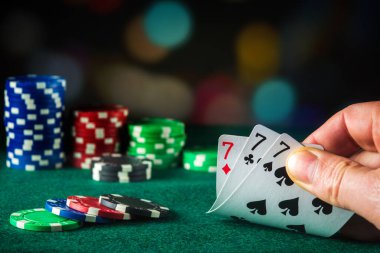 Poker kartları. Üçlü ya da set kombinasyonlu. Kumarbazın eli poker kulübünde kağıt oynar.