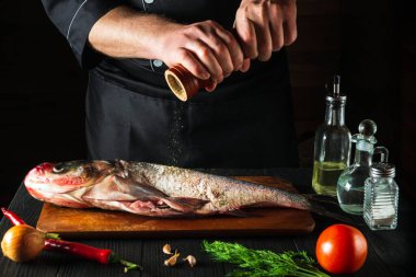 Aşçı taze balık kocakafalı sazan balığı serpiştiriyor. Balık yemi pişirmeye hazırlanıyorum. Restoranda ya da kafe mutfağında çalışma ortamı