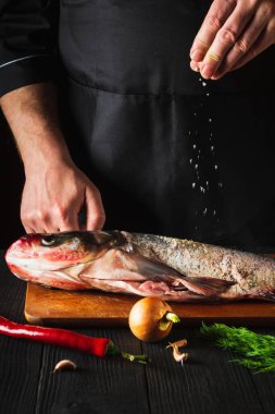 Şef taze balık kocakafalı sazan balığı hazırlıyor. İçindekilerle tuz serpiyor. Balık yemi pişirmeye hazırlanıyorum. Restoranın mutfağında çalışma ortamı