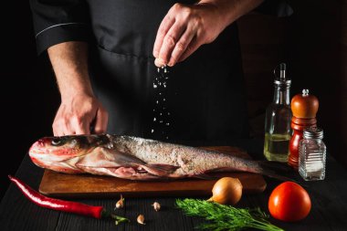 Şef taze balık kocakafalı sazan balığı hazırlıyor. İçindekilerle tuz serpiyor. Balık yemi pişirmeye hazırlanıyorum. Restoranın mutfağında çalışma ortamı