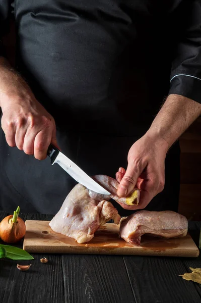 Restoranın mutfağında tavuk budu pişirmeye hazırlanıyorum. Şef kesme tahtasındaki bıçakla tavuk budu kesiyor. Izgara tavuk.