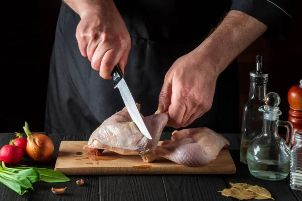 Restoranın mutfağında tavuk budu pişirmeye hazırlanıyorum. Şef kesme tahtasındaki bıçakla tavuk budu kesiyor.