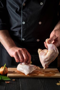 Restoranın mutfağında tavuk budu pişirmeye hazırlanıyorum. Şef çiğ tavuk budu tutuyor. Izgara tavuk.