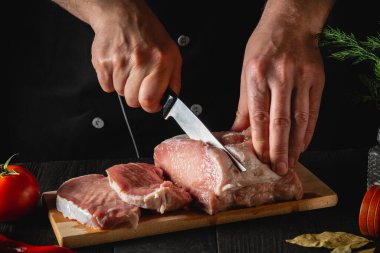 Şef Kasap mutfakta bıçakla et kesiyor, yemek pişiriyor. Mutfak masasında lezzetli bir öğle yemeği hazırlamak için sebze ve baharat var.